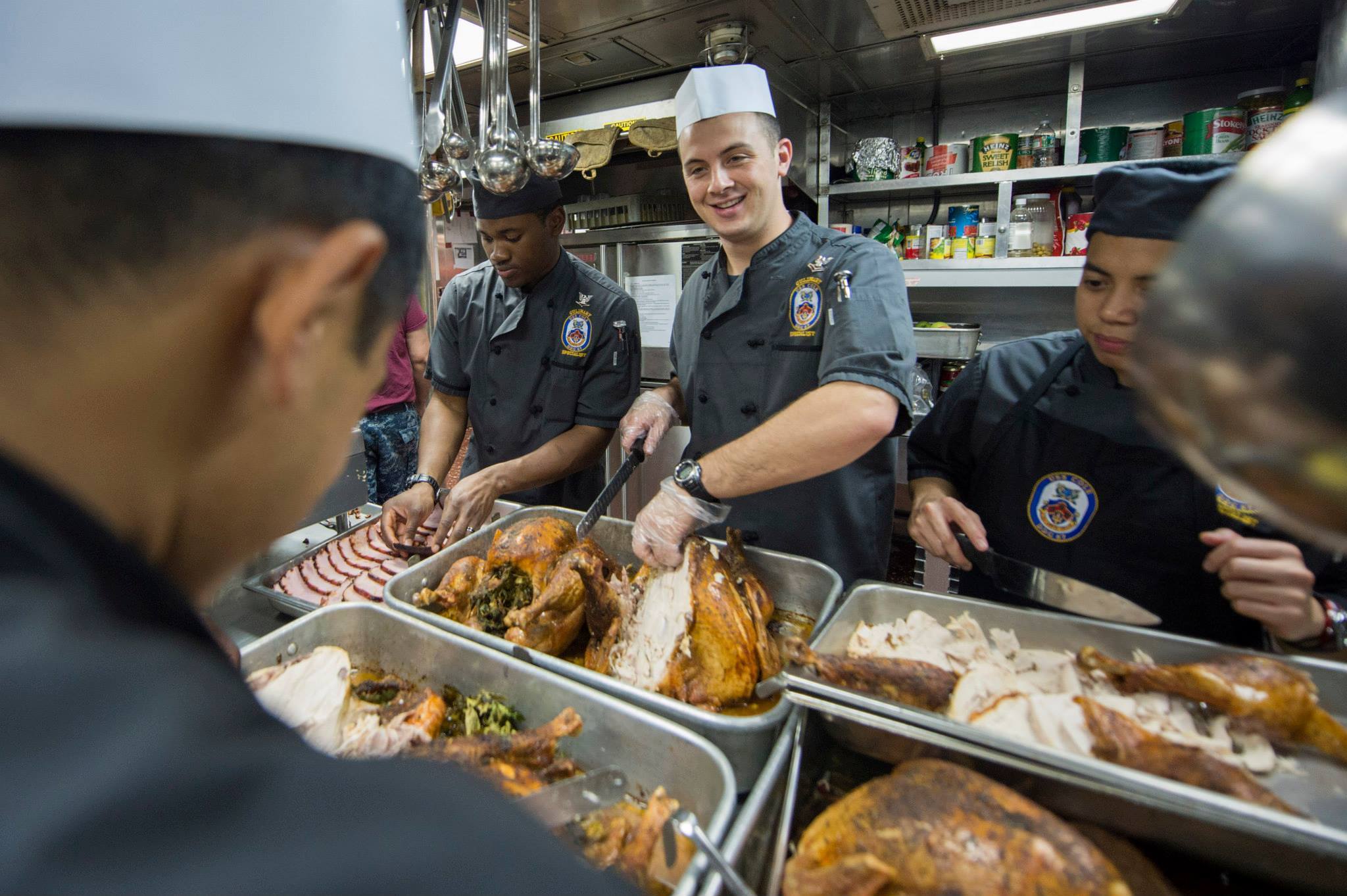 Service members carve trays of turkey