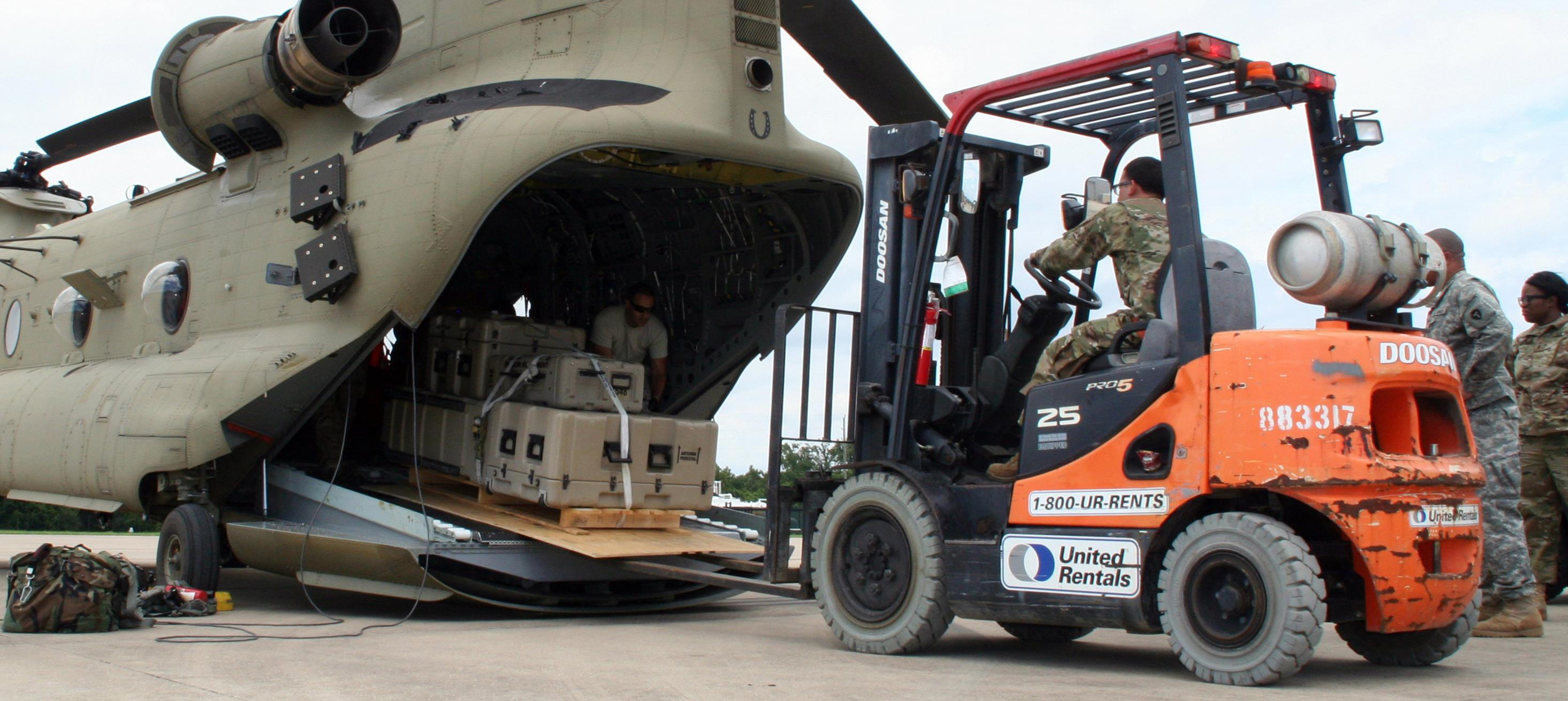 Image of a forklift driver loading a pallet of boxes onto the back of a military aircraft