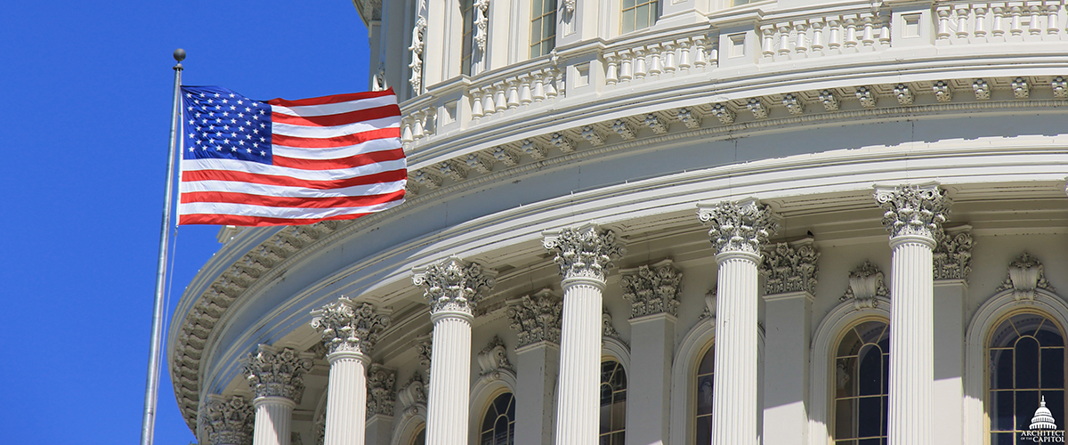 Close view of the U.S. Capitol dome with an american flag flying in front of it