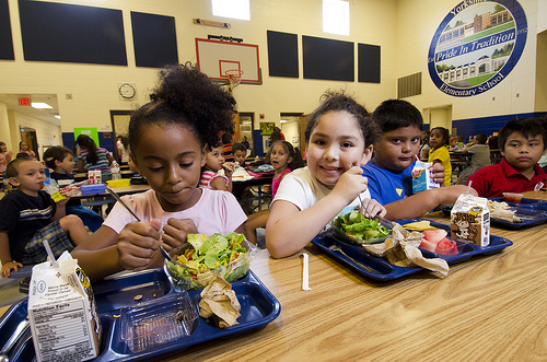 Children eating from a lunch tray in a large cateteria Children eating from a lunch tray in a large cateteria