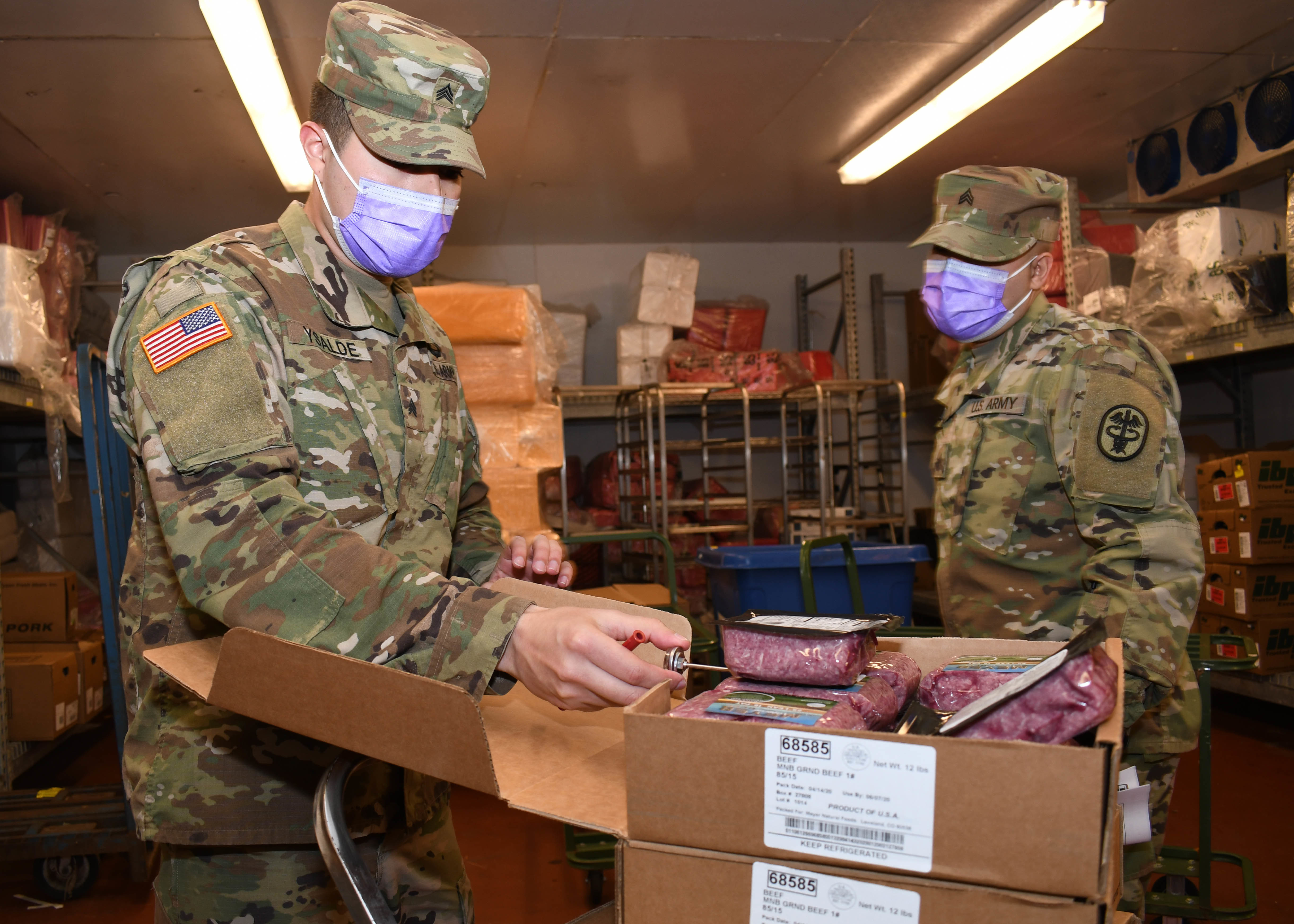 Two soldiers inspecting food out of a box