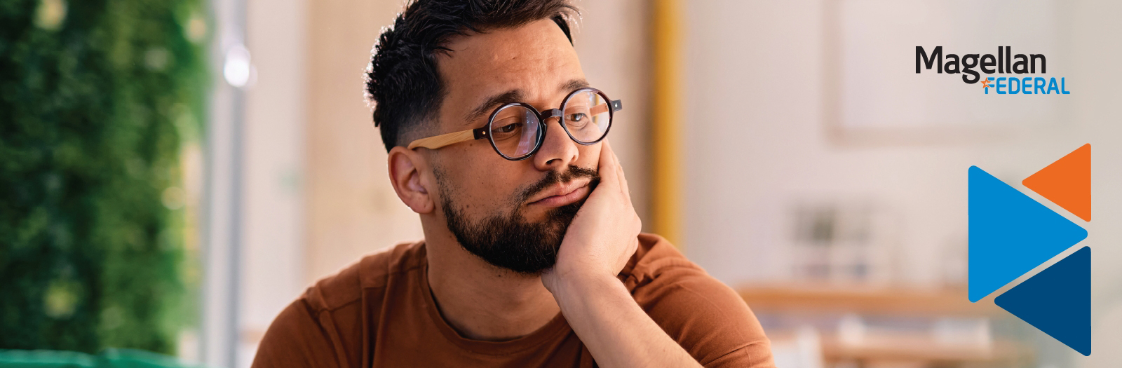 Man looking exhausted or suffering from burnout while resting head in hand.