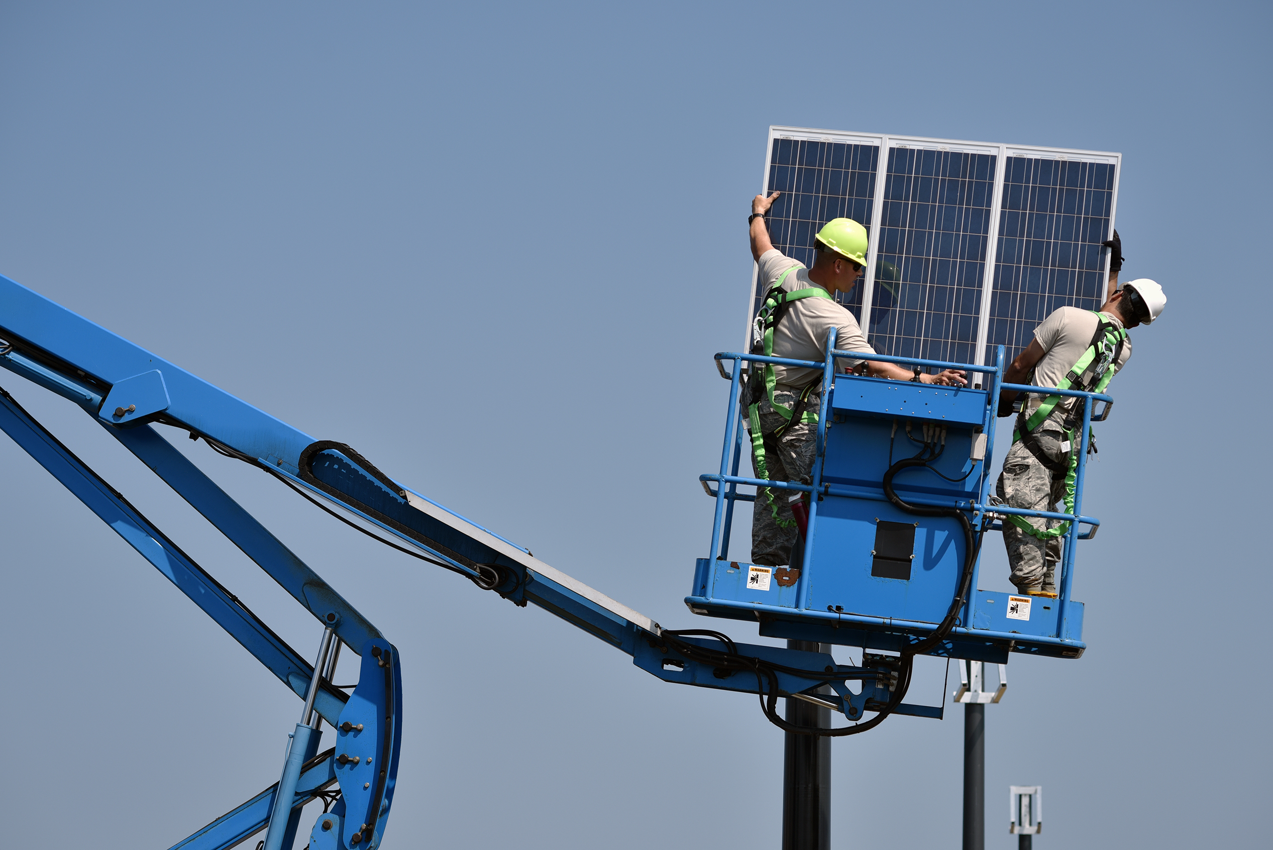 Workers in a lift with a solar panel