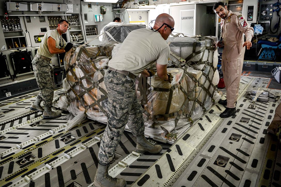 Servicemembers pushing a wrapped pallet of supplies